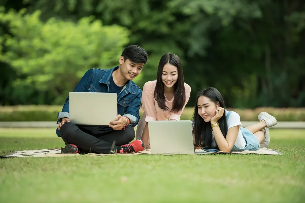 Ba bạn trẻ ngồi với máy tính xách tay trên bãi cỏ, minh hoạ việc lên kế hoạch sau khi nhận kết quả