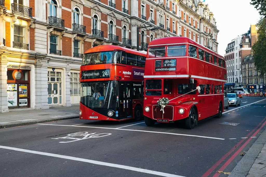 Hai chiếc xe buýt hai tầng màu đỏ chạy trên phố ở London, minh hoạ chuyến đi ngắn tới Anh