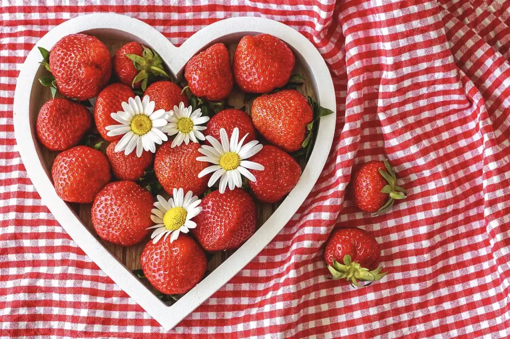 Khay dâu tây hình trái tim trên khăn picnic caro đỏ trắng, minh hoạ kỳ nghỉ dã ngoại ngày lễ