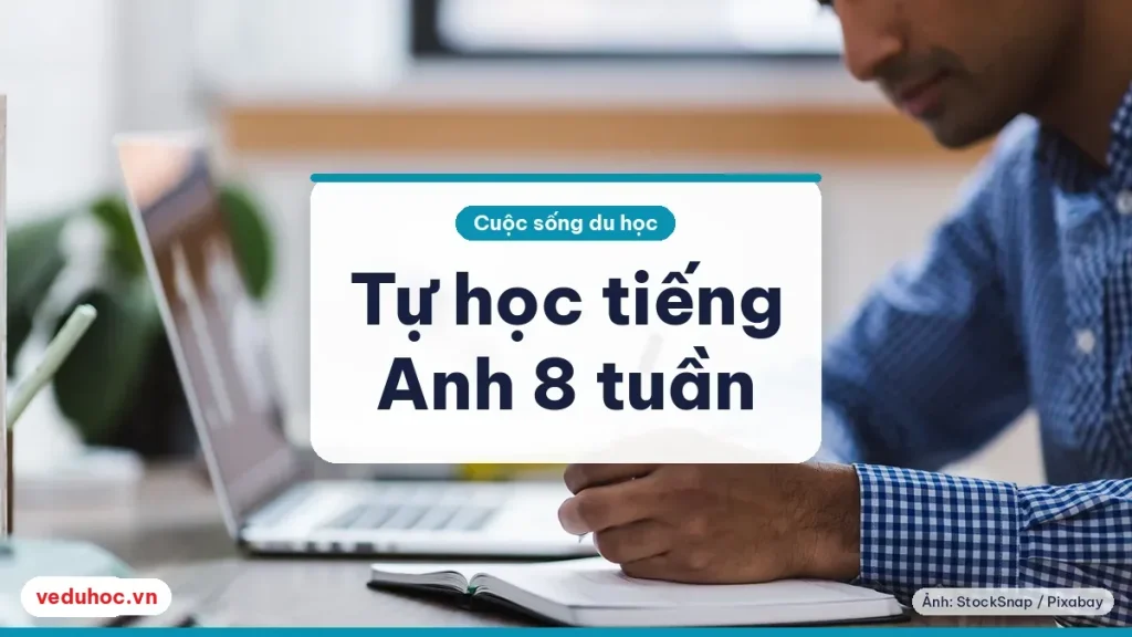 Laptop, sổ tay và bút đặt trên bàn học, dụng cụ tự học tiếng Anh trước ngày bay