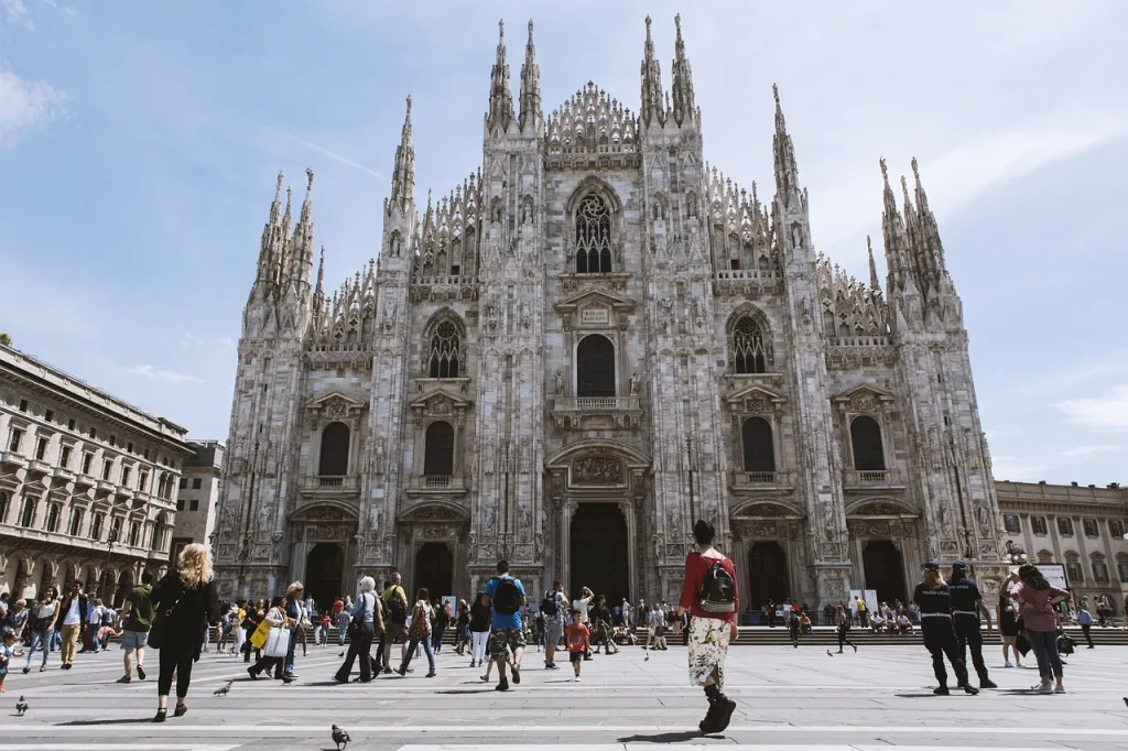 Mặt tiền nhà thờ lớn Duomo ở Milan dưới trời trong, vài du khách nhỏ phía trước quảng trường