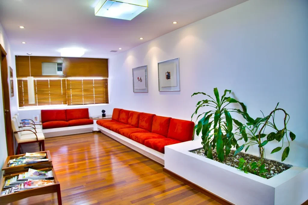 Phòng chờ sáng có ghế sofa đỏ và cây xanh, minh hoạ khu vực chờ trước buổi phỏng vấn visa