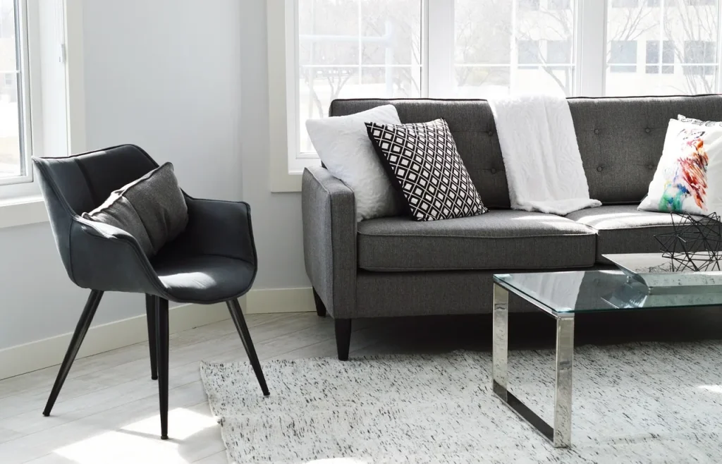 Phòng khách sáng với cửa sổ lớn, sofa và ghế bành, minh hoạ không gian trong nhà cần giữ không khí sạch khi trời khói