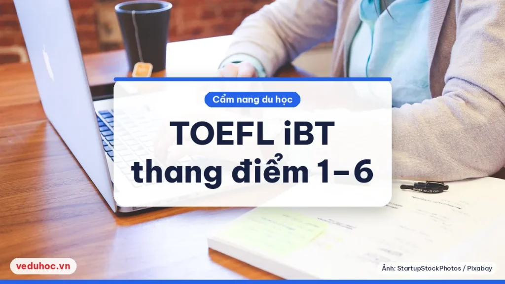 Hai tay gõ máy tính xách tay cạnh cốc và giấy ghi chú, hình dung làm bài thi TOEFL trên máy